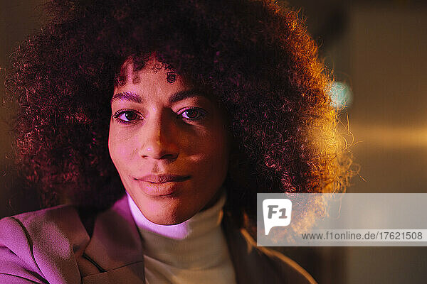 Businesswoman with curly hair in illuminated office