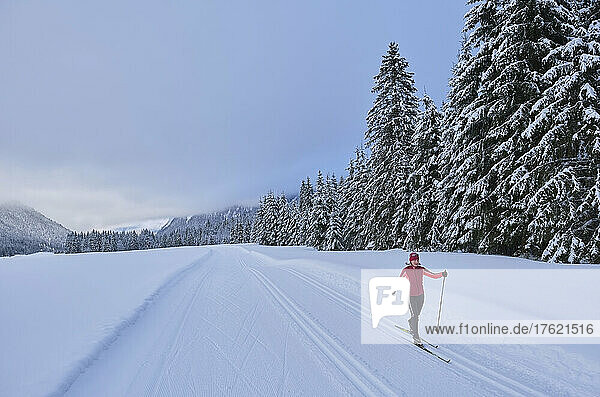 Aktive Seniorin fährt im Winterwald Ski