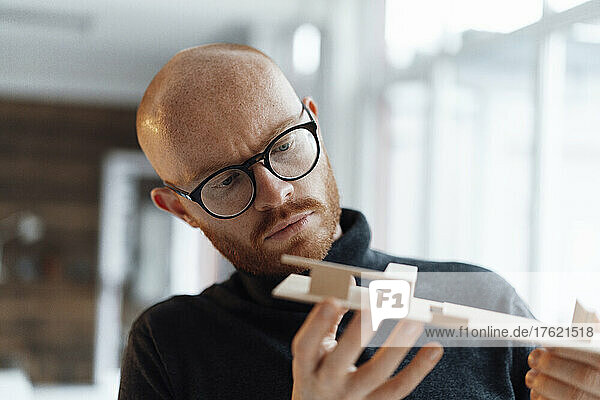 Young businessman examining wooden model in office