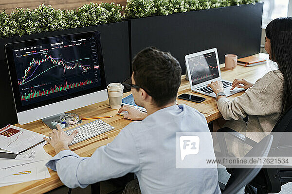Business colleagues working on cryptocurrency trading graphs in office