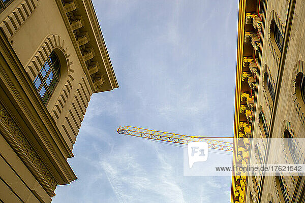 Germany  Bavaria  Munich  Low angle view of industrial crane standing over stucco cornices