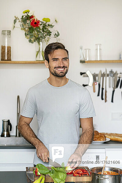 Lächelnder  gutaussehender Mann  der zu Hause in der Küche Essen hackt