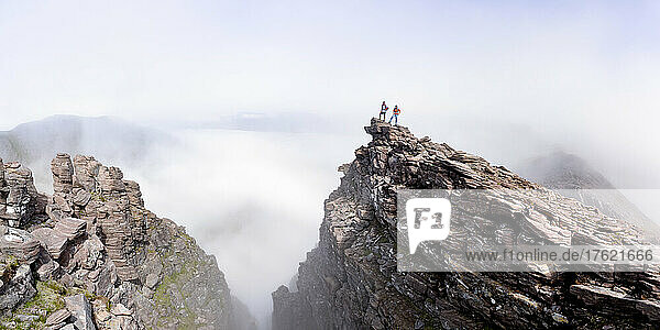 Man and woman standing on mountain cliff