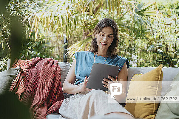 Businesswoman using tablet computer sitting on sofa