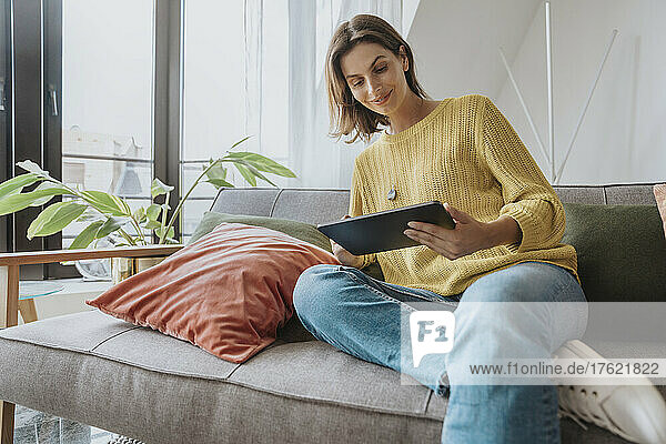 Frau sitzt auf Sofa und benutzt Tablet-PC
