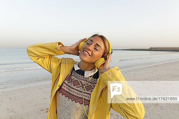 Happy woman enjoying music at beach