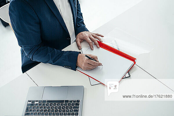 Businessman writing on file with pen in office