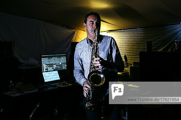 Musician with eyes closed practicing saxophone in recording studio
