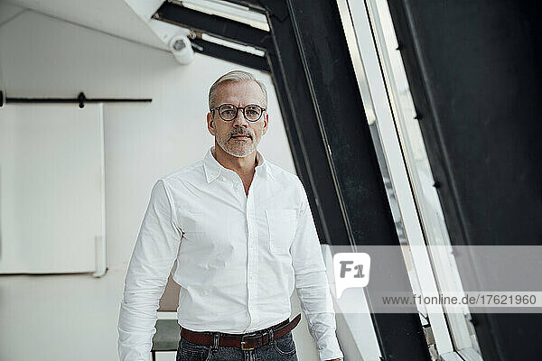 Confident businessman with eyeglasses at work place