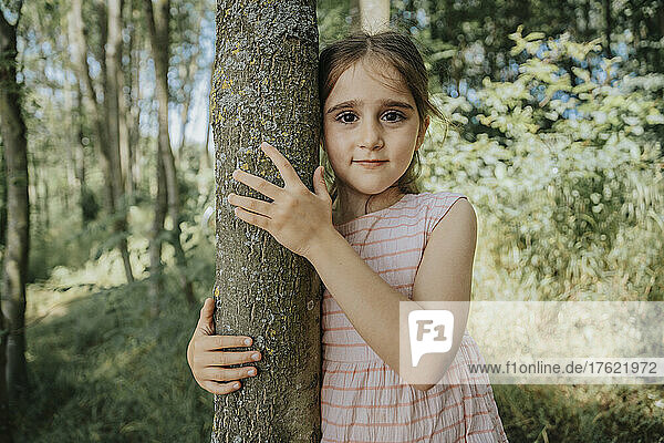 Innocent girl embracing tree in nature