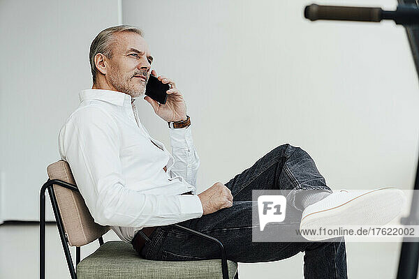Businessman talking on mobile phone sitting on chair at work place