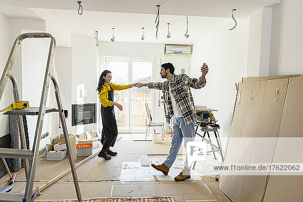 Junges Paar renoviert Haus und tanzt im Wohnzimmer