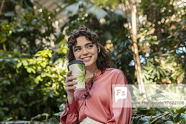 Smiling woman with disposable coffee cup in garden