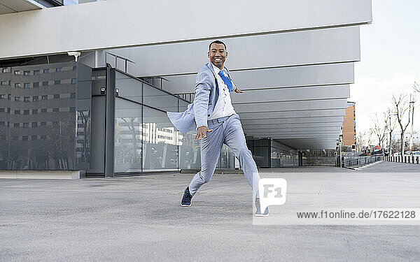 Smiling businessman dancing in front of building