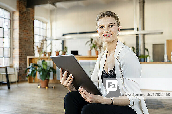 Smiling young businesswoman with tablet pc sitting in living room at home
