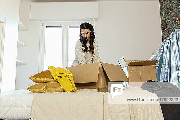 Junge Frau packt Kartons aus und zieht in neues Haus um