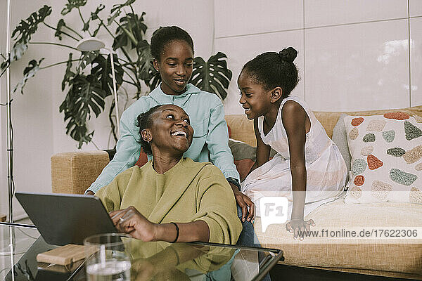 Happy mother talking with daughters in living room