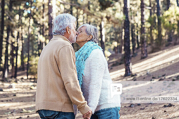 Affectionate senior couple kissing each other in forest