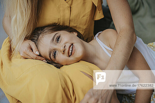 Smiling daughter lying on mother's lap at patio