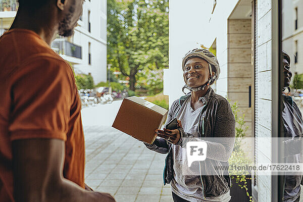 Smiling woman delivering package to customer