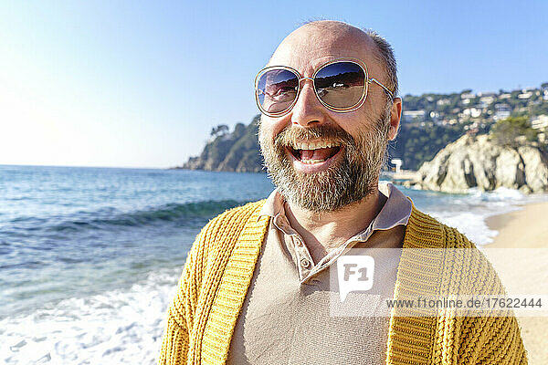 Man with sunglasses laughing at beach