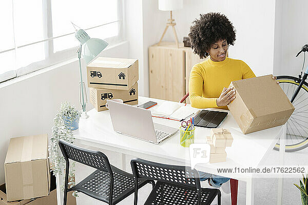 Young freelancer packing box sitting at table