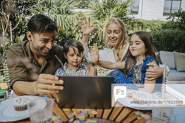 Familie winkt per Videoanruf über Tablet-PC im Hinterhof