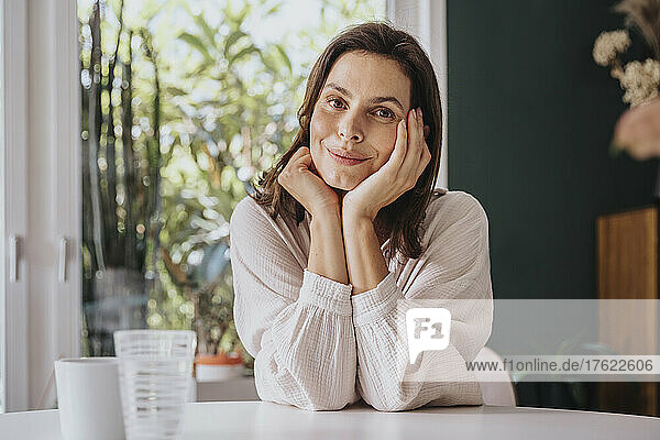 Smiling woman leaning on table at home