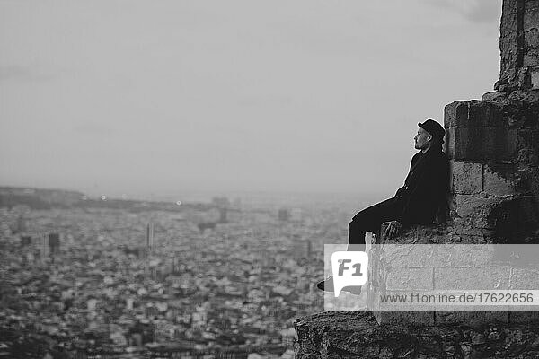 Contemplative man sitting on rock in city