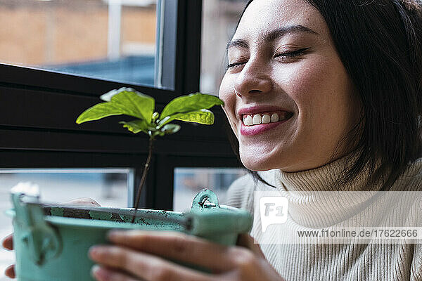 Smiling woman with eyes closed smelling plant