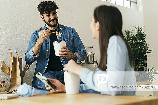 Man eating noodles spending leisure time with girlfriend at home