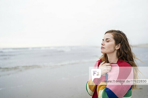 Beautiful woman with eyes closed standing at beach