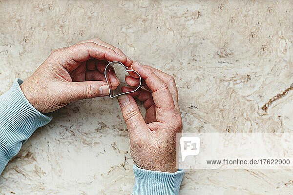 Senior woman holding heart shaped cookie cutter