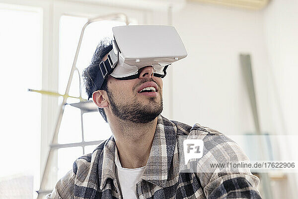 Young man watching through VR glasses at new home