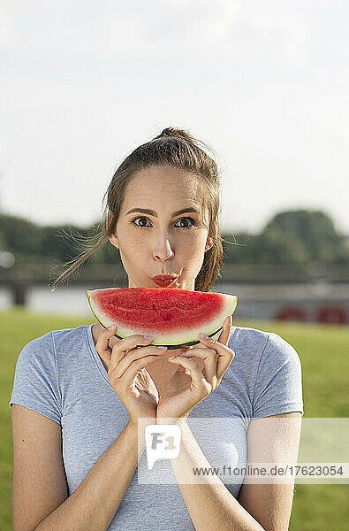 Young woman with slice of watermelon on sunny day