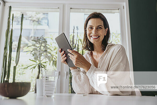 Woman with tablet PC smiling at home
