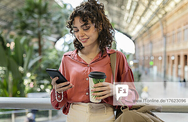 Young woman using smart phone at train station
