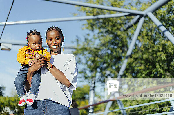 Happy young woman with cute daughter at park on sunny day