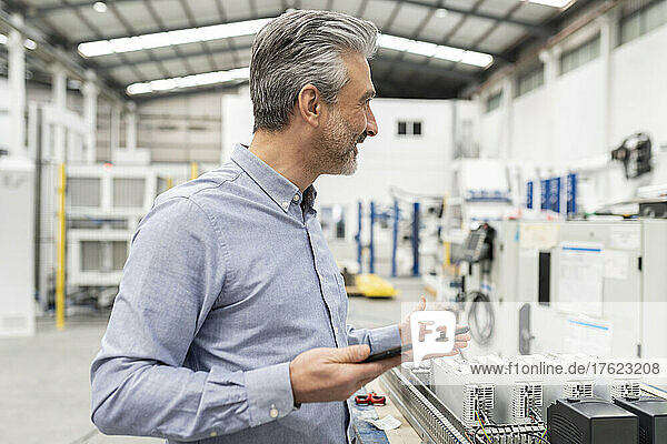Engineer holding tablet PC standing in factory