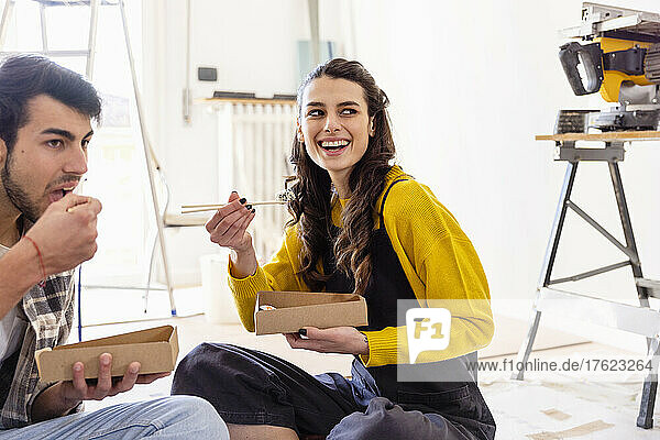 Smiling woman having food with boyfriend in new home