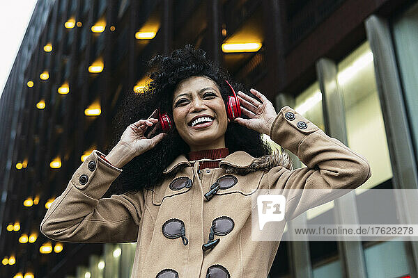 Happy woman listening music through wireless headphones enjoying in city
