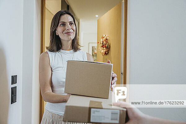 Smiling woman receiving packages from delivery person at door