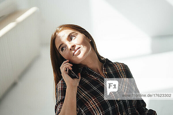 Young woman talking on smart phone at home