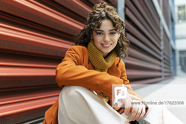 Smiling woman sitting on footpath