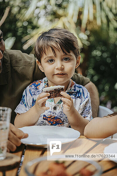 Netter Junge isst Cupcake auf einer Party im Hinterhof