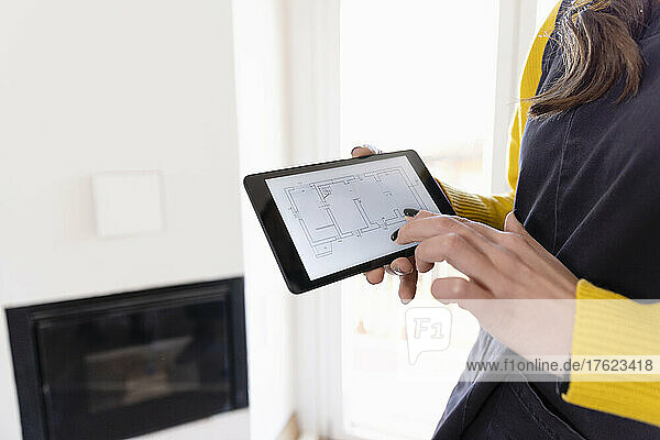 Woman with floor plan on tablet PC at home