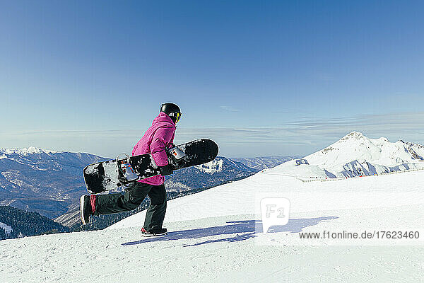 Man with snowboard running on snowy mountain
