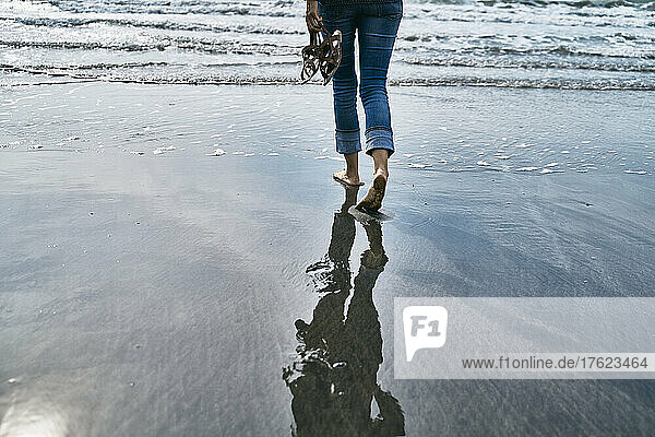 Woman walking on wet sand at beach