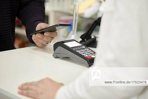 Kunde zahlt kontaktlos per Smartphone an der Kasse im Geschäft