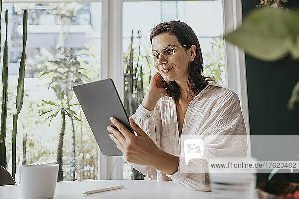 Lächelnde Frau  die zu Hause einen Videoanruf über einen Tablet-PC tätigt